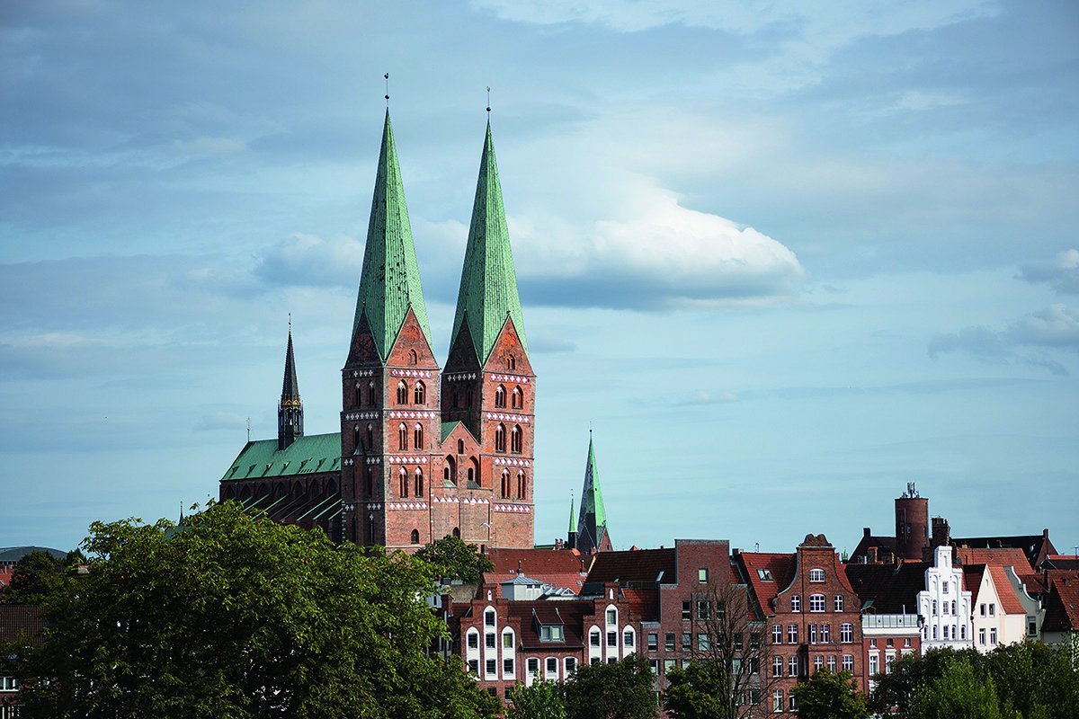 St. Marien ragt über den Altstadthäusern der Untertrave, rechtss daneben sieht man die Turmspitze von St. Aegidien. Der Himmel ist hell bewölkt - Copyright: Rainer Jensen