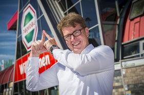 Jens-Dieter Haß macht das Sieben-Türme-Symbol mit seinen Zeigefingern. Die Finger zeigen eine Turmspitze.